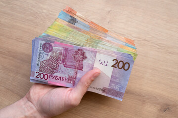 Belarusian paper money in hands on wooden background. Many currency banknotes of different denominations