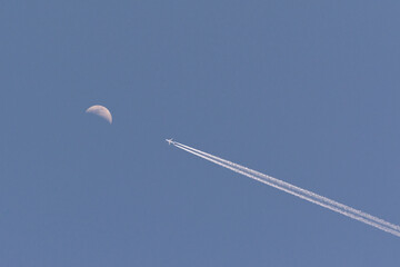 Vuelo comercial con estela de la propulsión a chorro con luna.