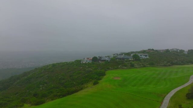 Forwards fly above golf course and luxury buildings surrounded by shrubs and green vegetation. Port Elisabeth, South Africa