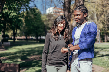 Laughing young indian sportswoman talking and having fun with her male african american friend before running outdoors