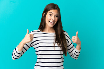 Teenager Brazilian girl over isolated blue background giving a thumbs up gesture