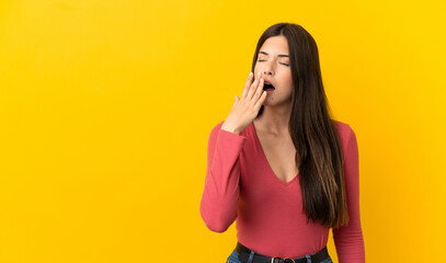 Teenager Brazilian girl over isolated yellow background yawning and covering wide open mouth with...