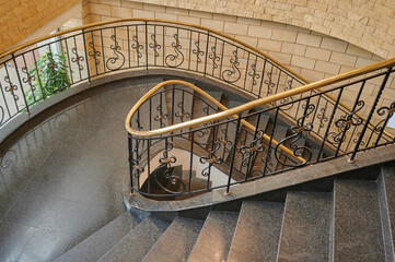 spiral staircase in the interior with marble floor and elegant wrought iron balusters with wooden...