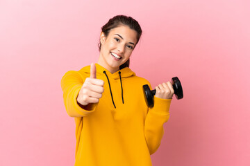 Young sport girl making weightlifting over isolated pink background with thumbs up because something good has happened