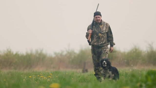 Hunter walks with dog on a hunt on a foggy lawn
