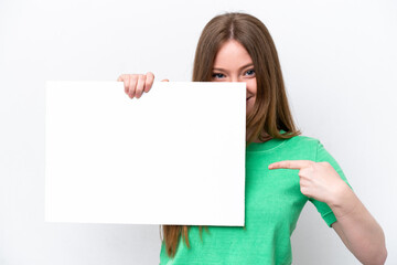Naklejka premium Young caucasian woman isolated on white background holding an empty placard and hiding behind it