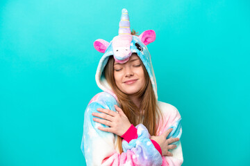 Young caucasian girl with unicorn pajamas holding pillow smiling with a sweet expression