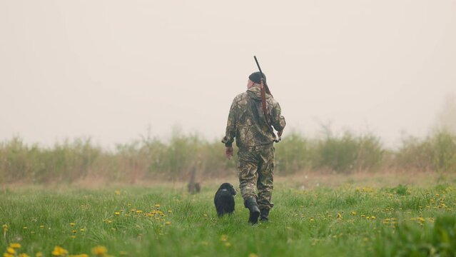 Hunter walks with dog on a hunt on a foggy lawn