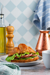 croissant with sausage, cucumbers and lettuce leaves  with coffe