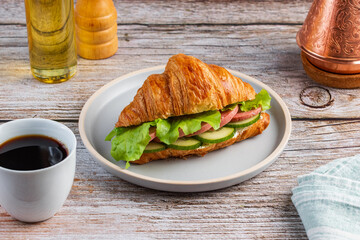 croissant with sausage, cucumbers and lettuce leaves  with coffe