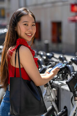 asian girl renting a city bike with her smartphone