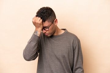 Young Brazilian man isolated on beige background with headache