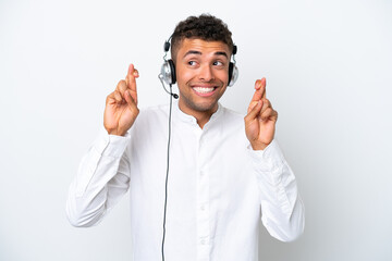 Telemarketer Brazilian man working with a headset isolated on white background with fingers crossing