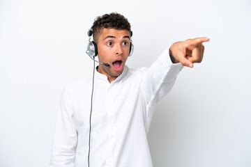 Telemarketer Brazilian man working with a headset isolated on white background pointing away