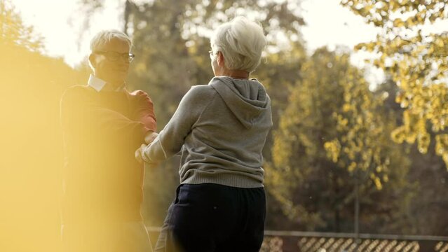 Middle aged Caucasian married people dance in park, holding hands and smiling medium shot . High quality 4k footage