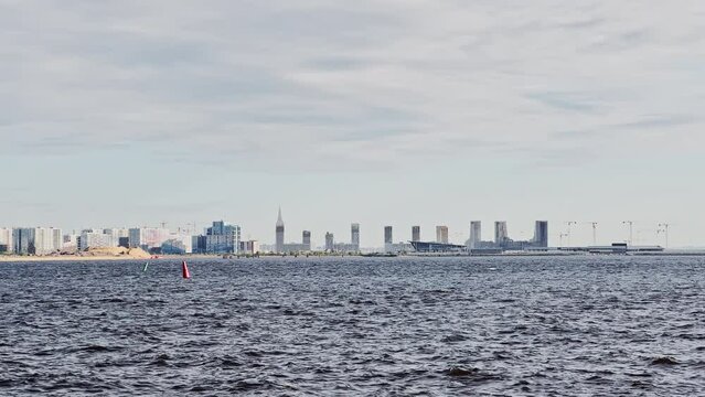 residential complex under construction on the embankment of the Neva River in sunny weather, bulk island, construction cranes