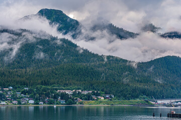 Juneau, Alaska, USA - July 19, 2011: Gray clouds captured in valley between 2 green pine covered...