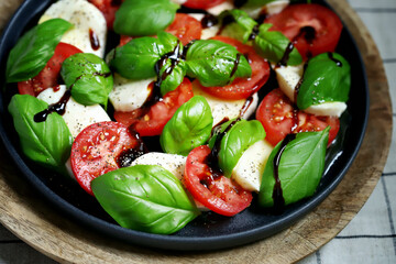 Soft focus. Classic caprese salad on a dark plate. Italian recipes concept.