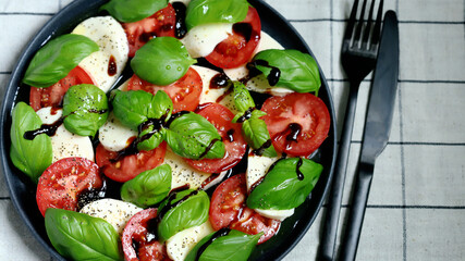 Soft focus. Classic caprese salad on a dark plate. Italian recipes concept.