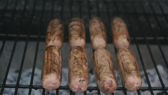Spicy Sausages Being Grilled Over Bright Glowing Coals Broasting On Fire. Lunch Celebration Party Barbecue. Outdoor Cooking. Cook Prepares Oriental Dish In Kitchen. Junk Food, Healthy Lifestyle.