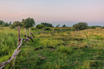 Old wooden fence in field at sunset