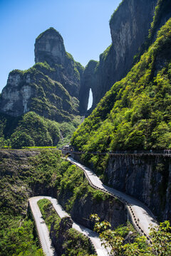 Road bends and Tianmen cave covered with green forest in Zhangjiajie, Hunan, China, vertical image with copy space for text