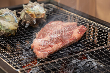 炭火で焼かれるサザエと牛肉　Turban shell and beef