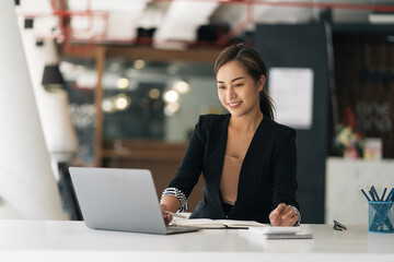 Cheerful business lady working on laptop in office, Asian happy beautiful businesswoman in formal...
