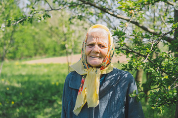 Portrait of an old happy woman in a yellow headscarf. Portrait of a gray-haired adult grandmother...