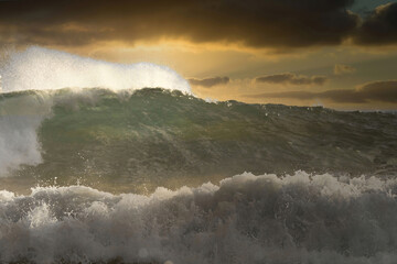 Large geen ocean wave following the previous wave at sunset.