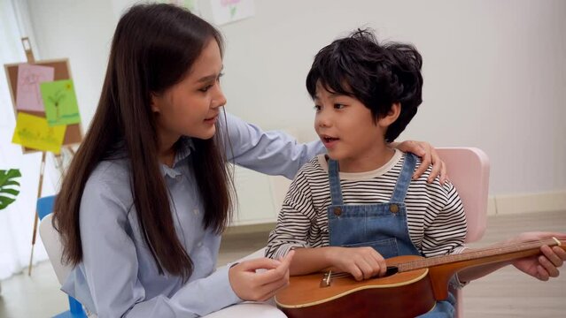 Back to school and summer course. Little children play guitar in kindergarten classroom.