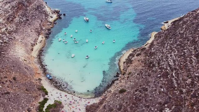 Aerial drone, Cala Pulcino in Lampedusa, tranquil cove with rugged landscape, clear waters, known as "caletta barche volanti" or "flying boats cove"