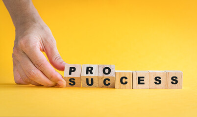 Success or process text. Wooden cube block flip over word process to success. On yellow background.