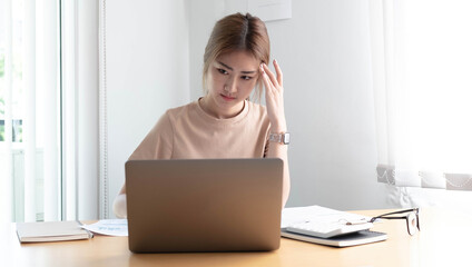 Young Asian woman feeling migraine head strain. Tired, Overworked businesswoman financier while working on laptop computer in office.