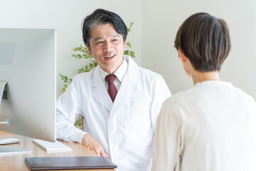 Obraz premium 女性を診察・カウンセリングする50代男性医師