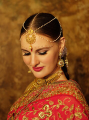 Lovely young woman wearing traditional indian wedding sari and jewelry, beauty smiles and looks down