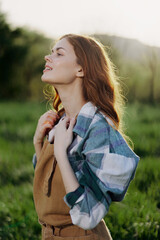 Portrait of a young girl on a summer day in the rays of the setting sun with a beautiful smile, dressed as a farmer and gardener