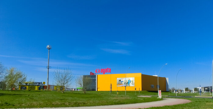 Logo of the Agata Meble furniture store with an advertisement banner on the yellow wall