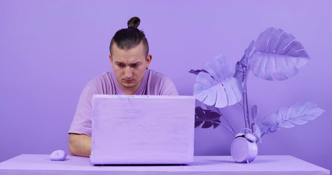 Room and objects in the same lilac color. Office in monochrome minimalist style. The designer at the computer. Fashion trends in modern interior design.