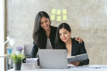 Group of young asian business people discussing something and smiling while sitting at the office table, two business people in the office working together.