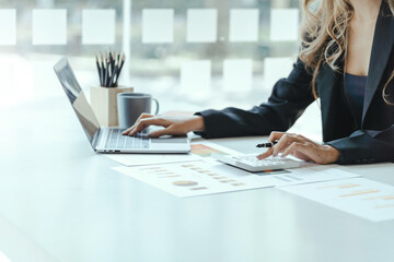 Asian female accountant or banker making calculations. Savings, finances and economy concept through a laptop.