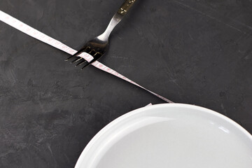 a plate wrapped with a centimeter and a fork on a black background with a copy space concept diet nutrition
