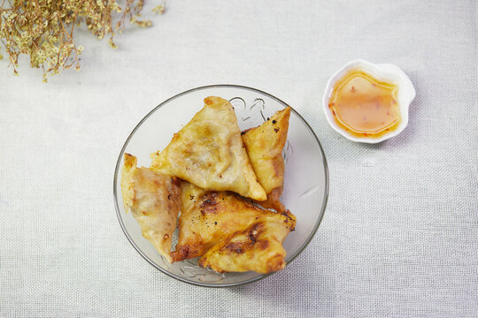 Fried samosa in a glass bowl with sauce
