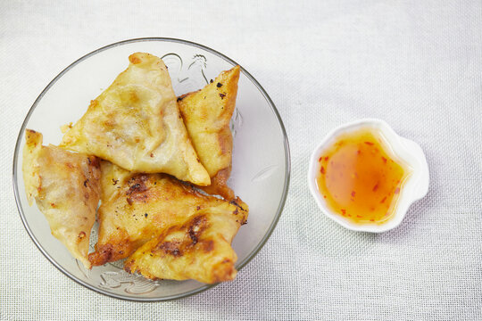 Fried samosa in a glass bowl with sauce
