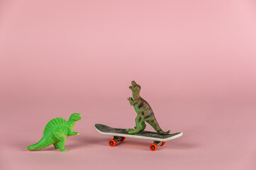 Two miniature dinosaurs and a mini skateboard against the pink background. Small green miniatures...