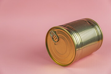 Canned Food. A gold can against a pink background. Selective focus.