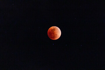 lunar eclipse. Image of a red moon in a clear sky with stars