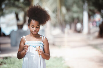 African American Little girl eating ice cream cone in the outdoor park