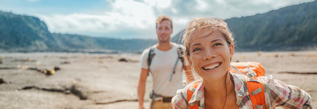 Travel hiking couple hikers happy with backpacks on summer outdoor active adventure vacation. Smiling Asian girl and man hikers banner landscape panoramic