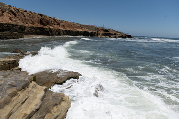 Splash wave rolls over ocean rocks
